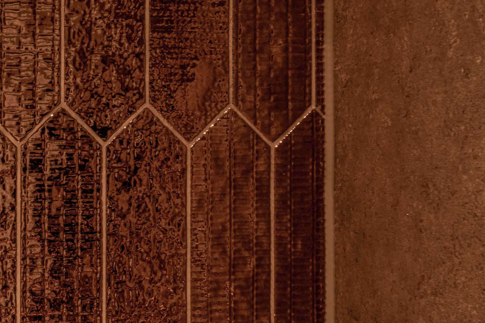 Detail van de bronskleurige wandtegels in het toilet door Keistad Tegelwerken